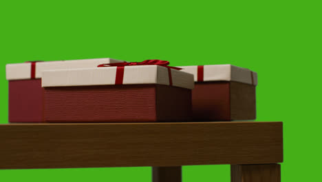 Close-Up-Of-Gift-Wrapped-Present-Boxes-On-Table-Shot-Against-Green-Screen-1